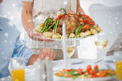 Woman bringing a roast chicken in the dining room