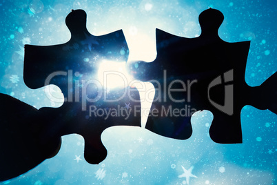 Composite image of hand holding two jigsaw pieces