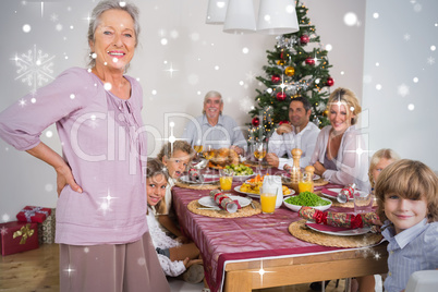 Composite image of grandmother standing beside dinner table