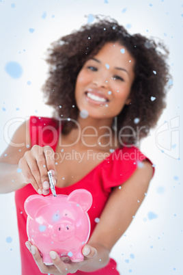 Composite image of money been put into a pink piggy bank