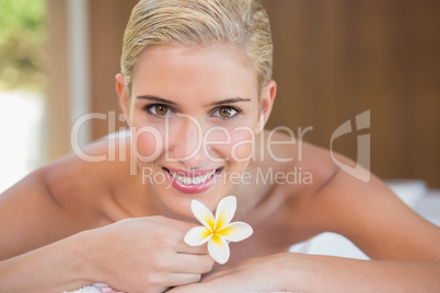 Woman holding flower on massage table at spa center Woman holding flower on massage table at spa center