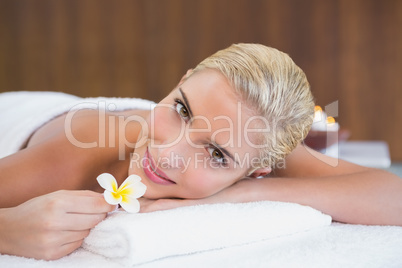 Woman holding flower on massage table at spa center