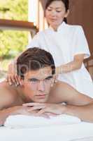 Young man receiving shoulder massage at spa center