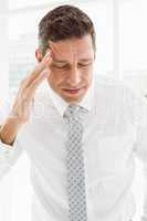 Young businessman with severe headache in office