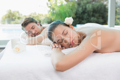 Couple lying on massage table at spa center