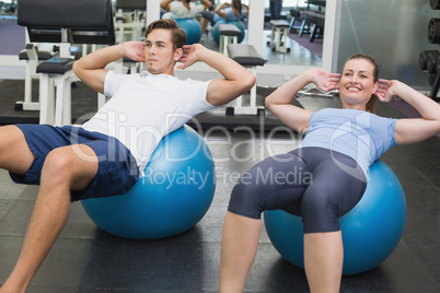 Couple doing sit ups on exercise balls