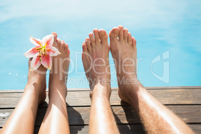 Couple feet against swimming pool on a sunny day