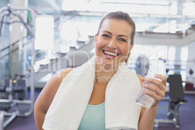Fit brunette smiling at camera with towel around shoulders