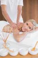 Woman receiving back massage at spa center