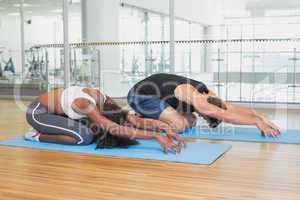 Fit couple in childs pose on exercise mats
