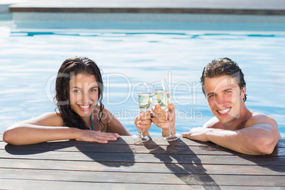 Couple toasting champagne in swimming pool