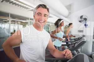 Fit man running on treadmill smiling at camera