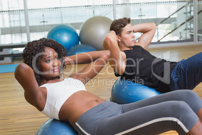 Couple doing sit ups on exercise balls