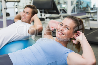 Couple doing sit ups on exercise balls