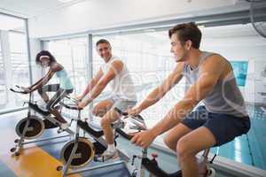 Three fit people working out on exercise bikes