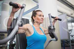 Fit brunette using weights machine for arms