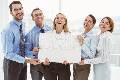 Cheerful business people holding blank board in office