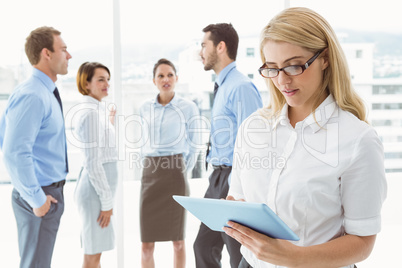 Businesswoman using digital tablet with colleagues behind