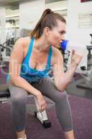 Fit brunette drinking from sports bottle