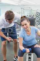 Personal trainer helping client lift dumbbell