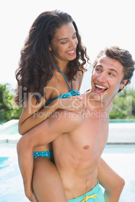 Man carrying cheerful woman by swimming pool