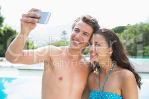 Couple taking picture of themselves by swimming pool