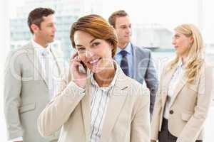 Businesswoman using mobile phone with colleagues behind