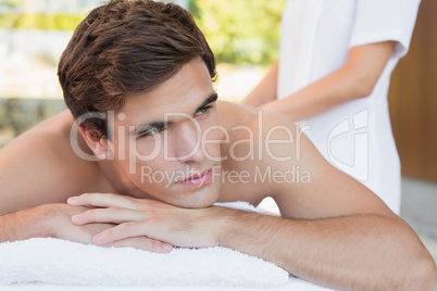 Young man lying on massage table at spa center