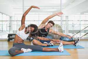 Fit couple warming up on exercise mats