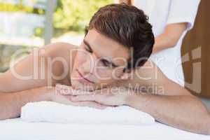 Young man lying on massage table at spa center
