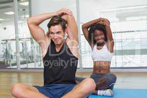 Fit couple warming up on exercise mats