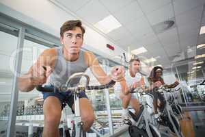 Three fit people working out on exercise bikes