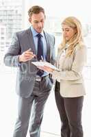 Businessman and secretary looking at diary in office