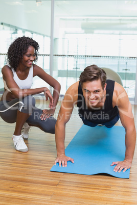 Personal trainer working with client on exercise mat Personal trainer working with client on exercise mat