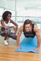 Personal trainer working with client on exercise mat