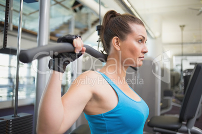 Fit brunette using weights machine for arms