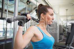 Fit brunette using weights machine for arms