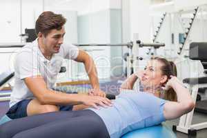 Personal trainer working with client on exercise ball