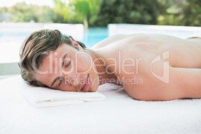 Handsome man lying on massage table at spa center