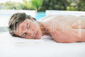 Handsome man lying on massage table at spa center