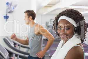 Fit woman smiling at camera on treadmill