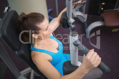 Fit brunette using weights machine for arms