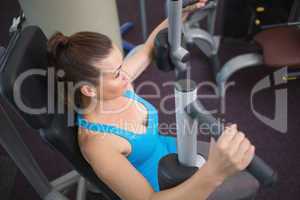 Fit brunette using weights machine for arms