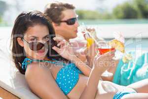 Couple with drinks by swimming pool