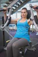 Fit brunette using weights machine for arms