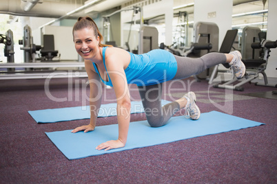 Fit brunette doing pilates on exercise mat