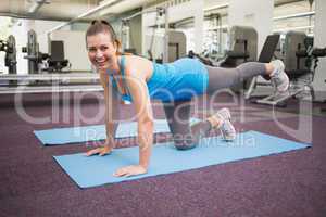 Fit brunette doing pilates on exercise mat