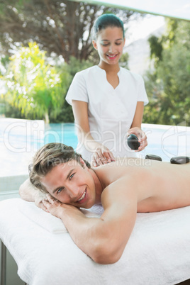 Handsome man receiving stone massage at spa center