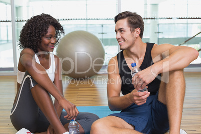 Personal trainer and client smiling at each other on exercise ma
