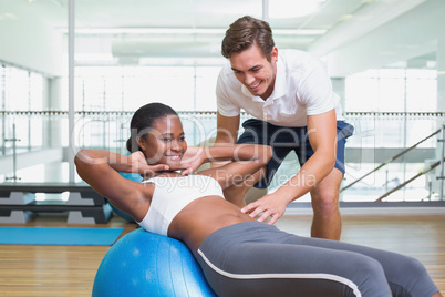 Personal trainer working with client on exercise ball